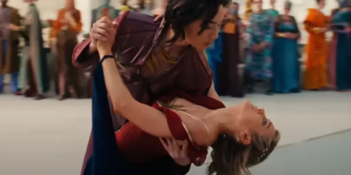 Prince Yan dips Carol Danvers as they dance. Carol is wearing a red dress with her iconic gold star on the chest.