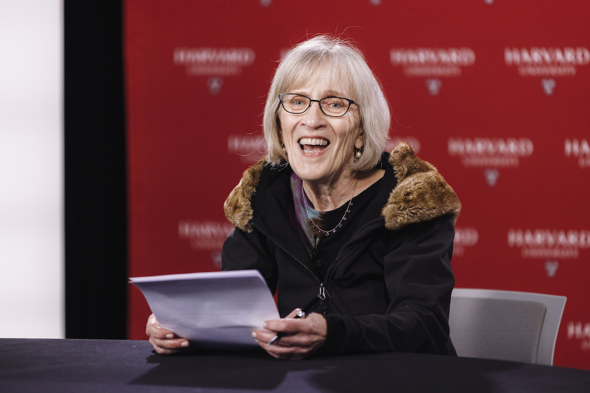 Claudia Goldin grins while sitting at a desk.