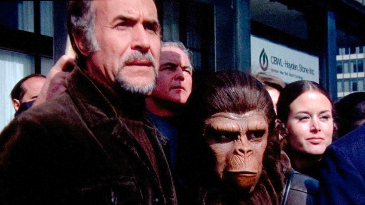Humans and apes stand together looking somber in "Conquest for the Planet of the Apes"