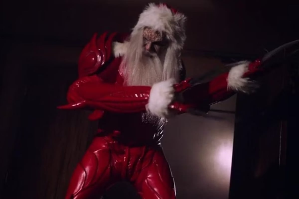 Still from A Creepshow Holiday Special: Shapeshifters Anonymous; Tom Glynn as Kringle wears a red santa suit style of armour with long pale hair.