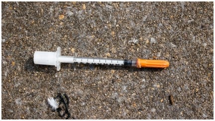 A used fentanyl syringe lies on the ground.
