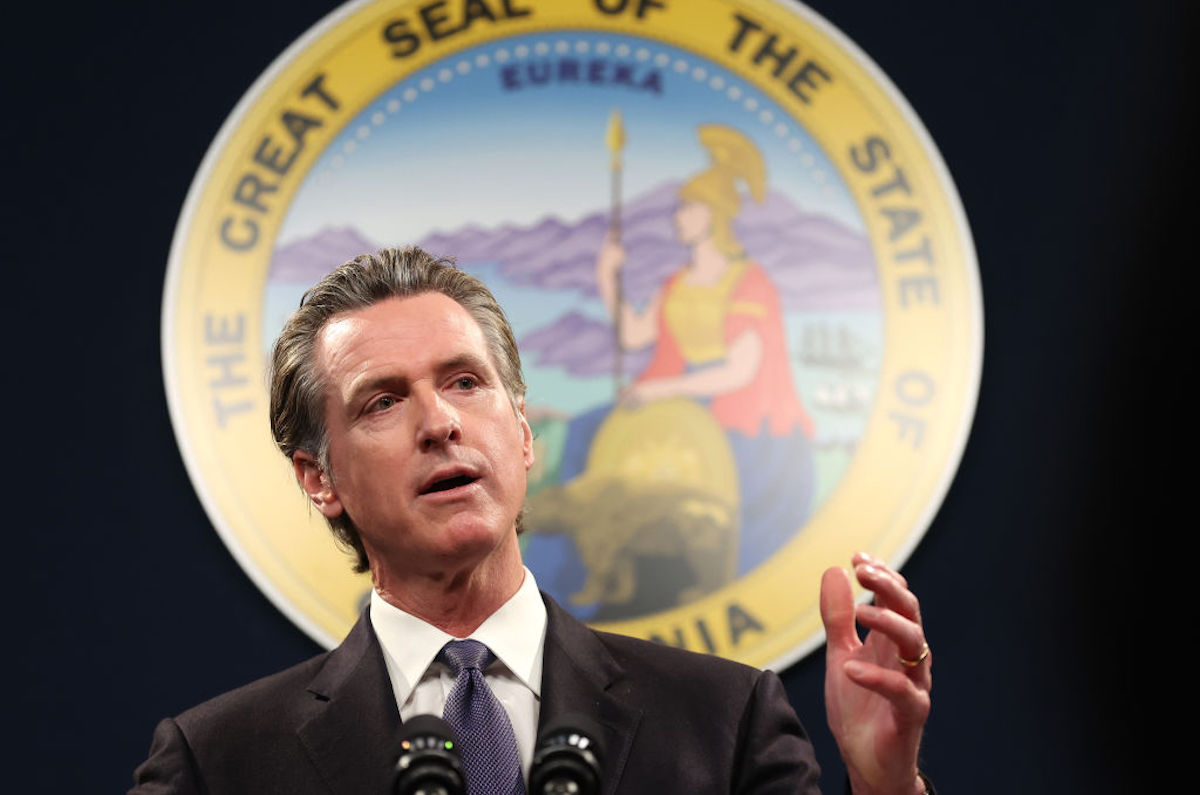 Gavin Newsom speaks standing in front of the California seal.