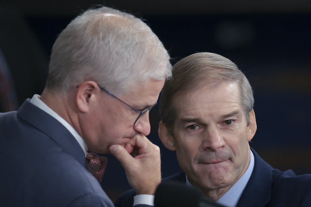 Jim Jordan bites his lip while leaning in to talk with another old white guy congressman.