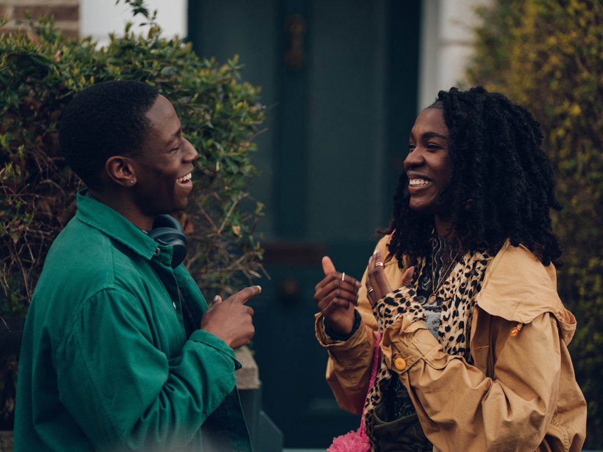 David Jonsson as Dom and Vivian Oparah Yas in 'Rye Lane' laughing with each other outside a house.