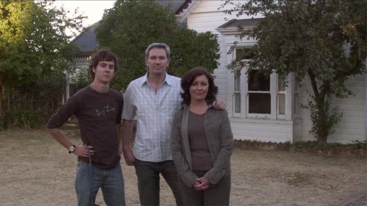 A father, mother, and son pose for a family photo outside of their house in "Lake Mungo"