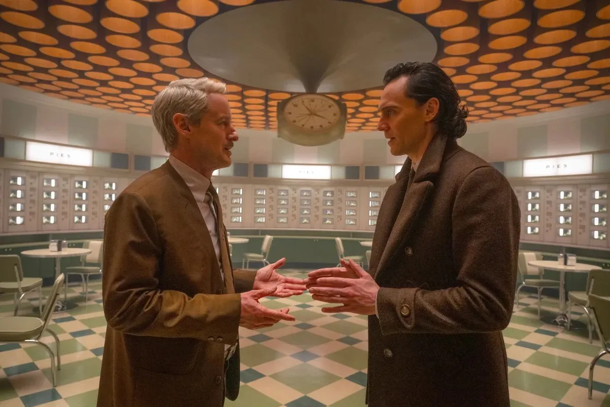 Mobius and Loki stand in the TVA automat, their hands outstretched as they talk to each other.