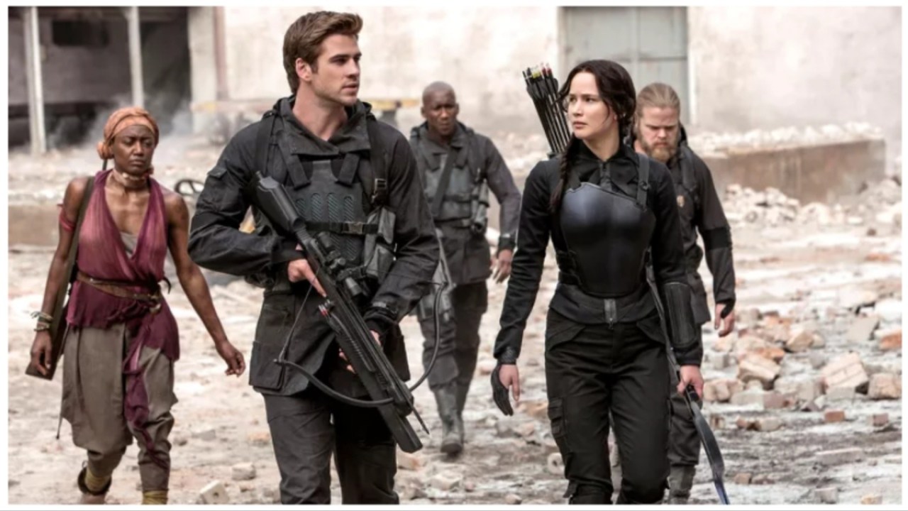Gale (Liam Hemsworth) and Katniss (Jennifer Lawrence) explore a wartorn region carrying weapons in 'The Hunger Games: Mockingjay Pt. 1'.