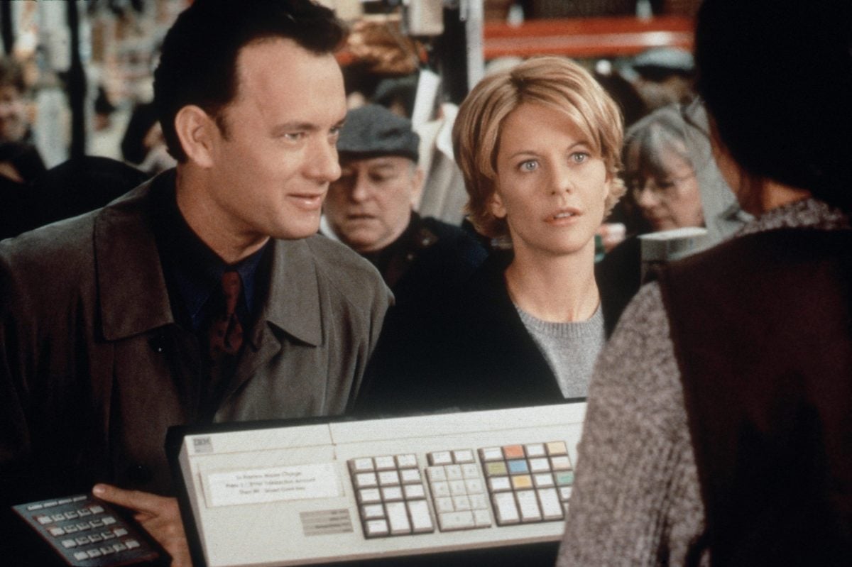 Meg Ryan as Kathleen Kelly and Tom Hanks as Joe Fox in 'You've Got Mail' standing next to each other in a grocery store.