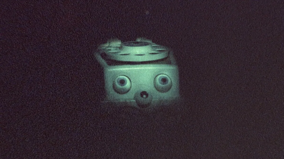 A spooky children's toy phone stares in the darkness in "Skinamarink"