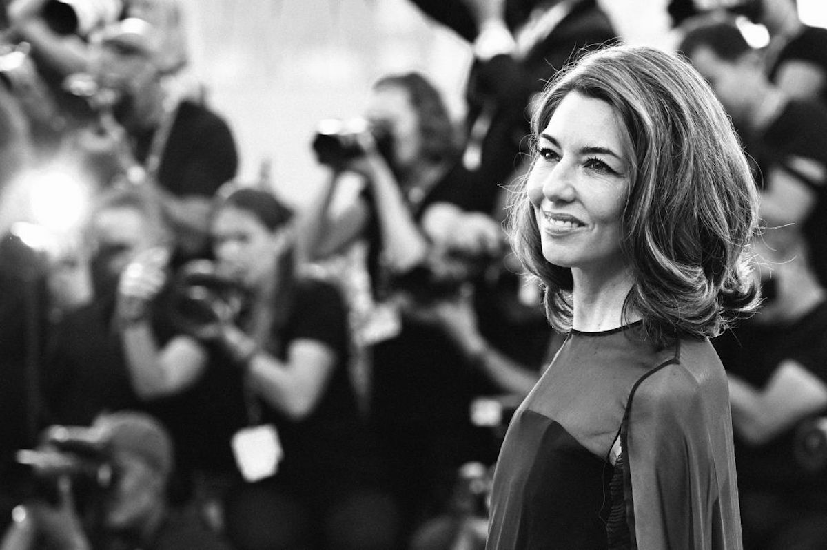A black and white image of Sofia Coppola smiling on a red carpet.