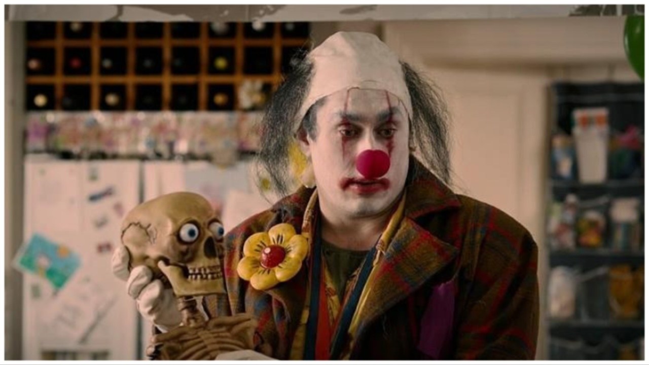 Ross Noble as Stitches the Clown holding fake skeleton in 'Stitches'.