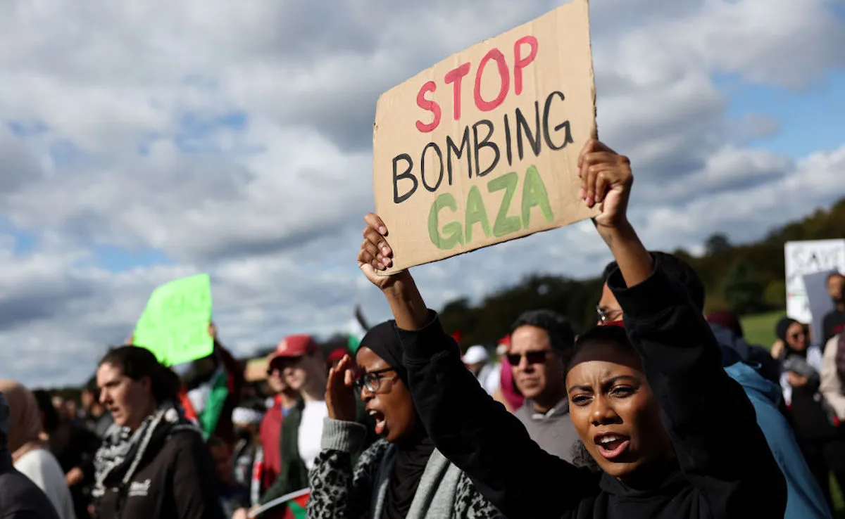 A woman holds up a sign saying "stop bombing Gaza" at a protest.