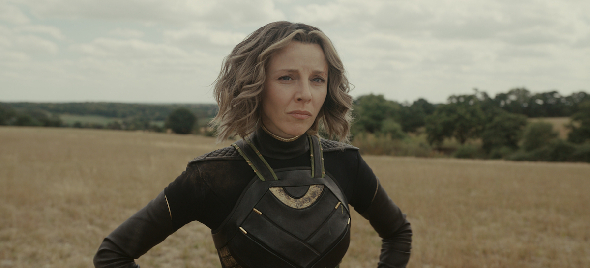 Sylvie stands with her hands on her hips in a field. She's still wearing her clothes from Loki season 1.