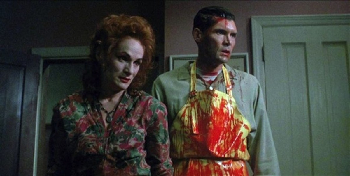 A man in a bloody apron stands with a pale woman in "The People Under The Stairs"