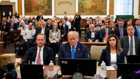 Donald Trump sits at the defendants' table in a courtroom, looking dejected.