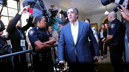 Michael Cohen walks by police and reporters outside court.