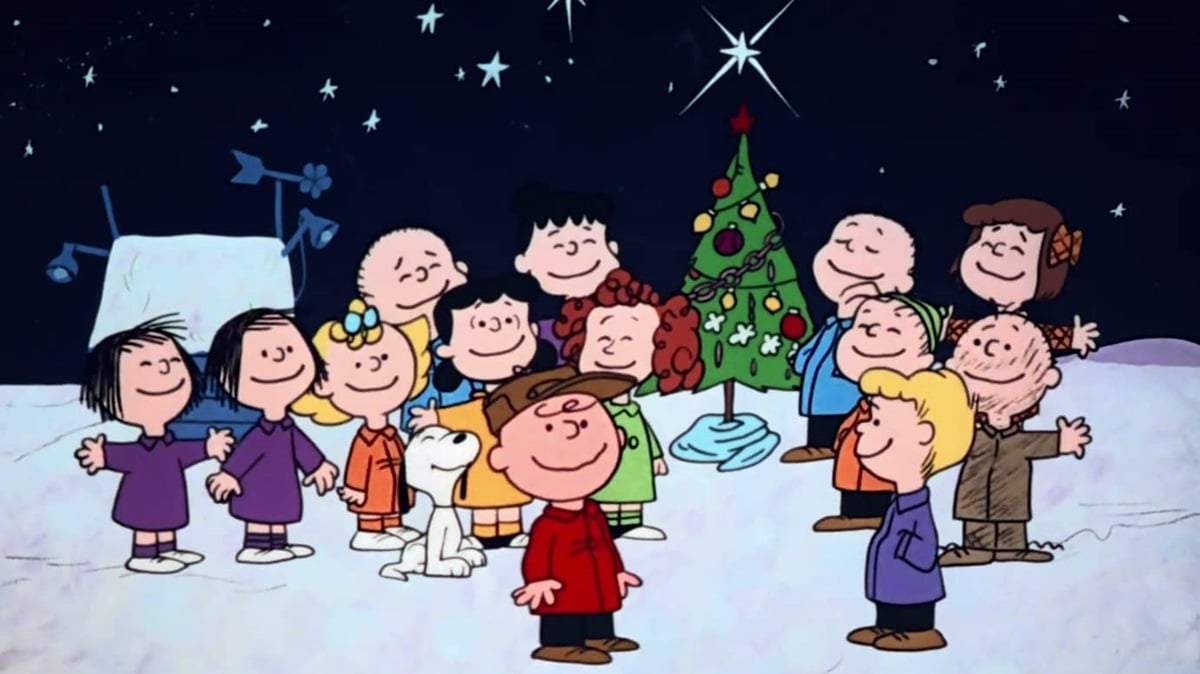 The Peanuts gang gathers around Charlie Brown and a Christmas tree