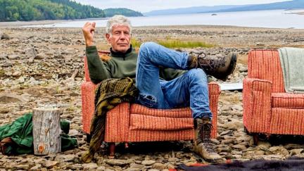 Anthony Bourdain, a man sits in an old armchair on a beach in promo image for 'Parts Unknown.'