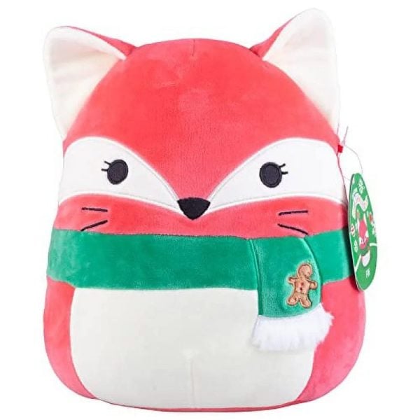 A red fox Squishmallow with a white stomach and a green scarf with a gingerbread man on it