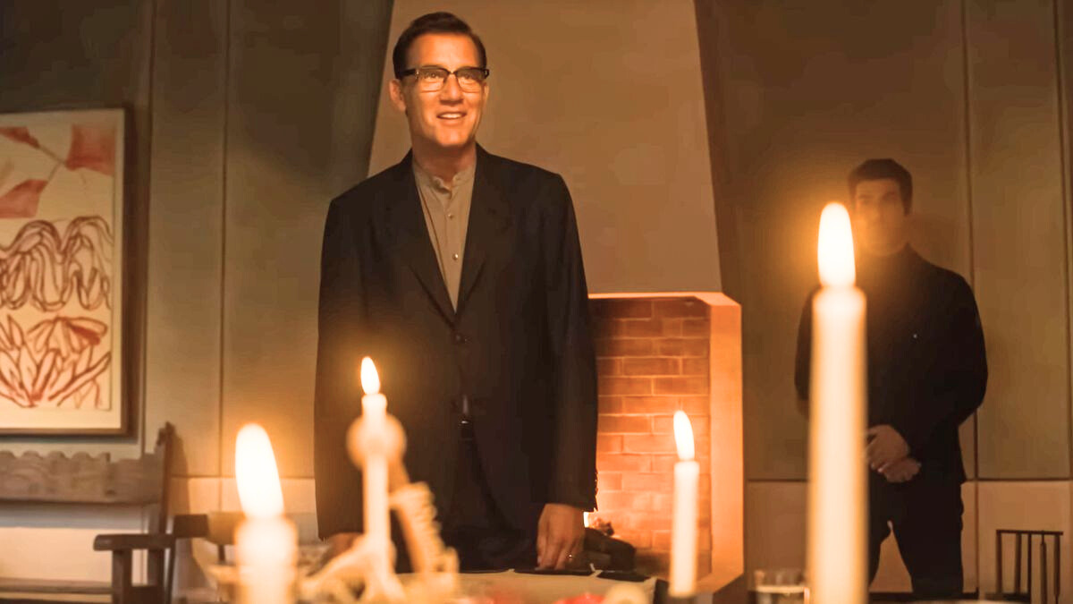 man stands smiling at the end of a candlelit dinner table