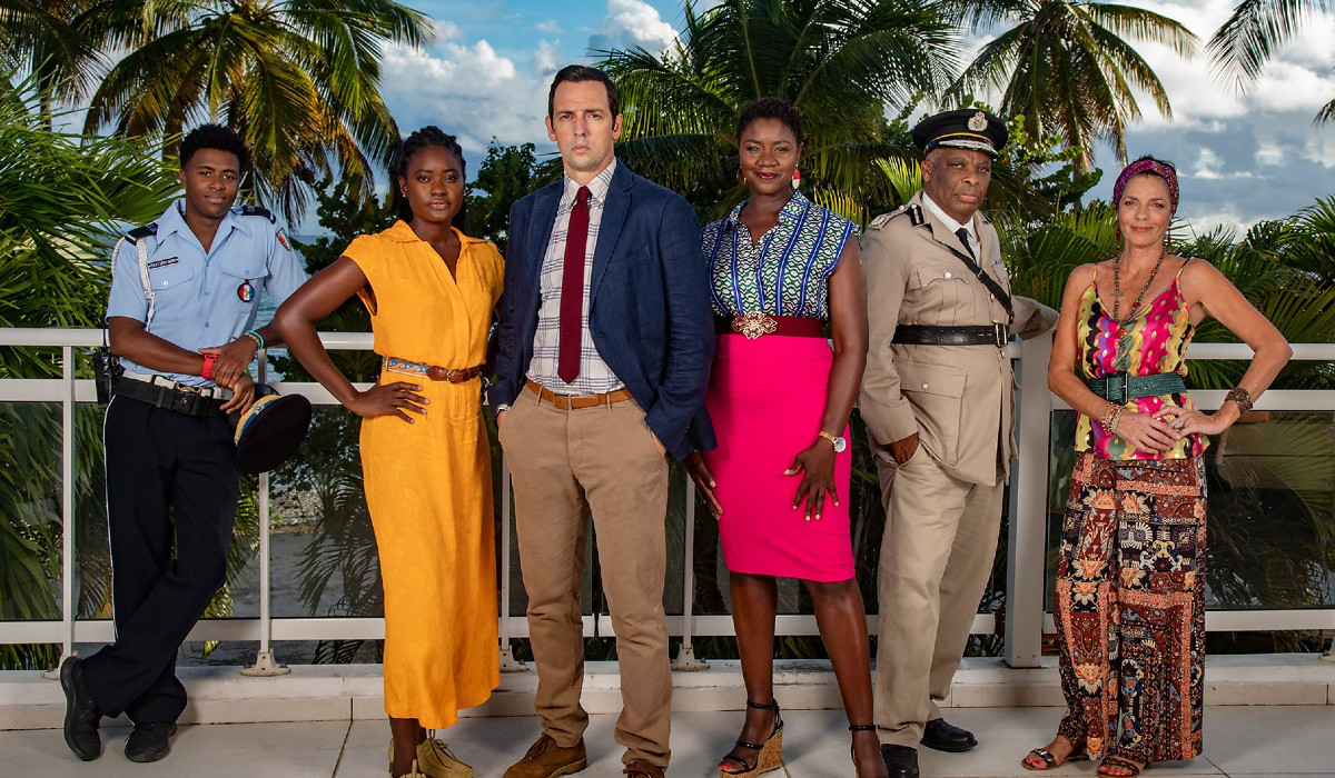 The Death in Paradise cast for season 12. From left to right: Tahj Miles as Marlon Pryce, Shantol Jackson as Naomi Thomas, Ralf Little as Neville Parker, Ginny Holder as Darlene Curtis, Don Warrington as Selwyn Patterson, and Elizabeth Bourgine as Catherine Bordey