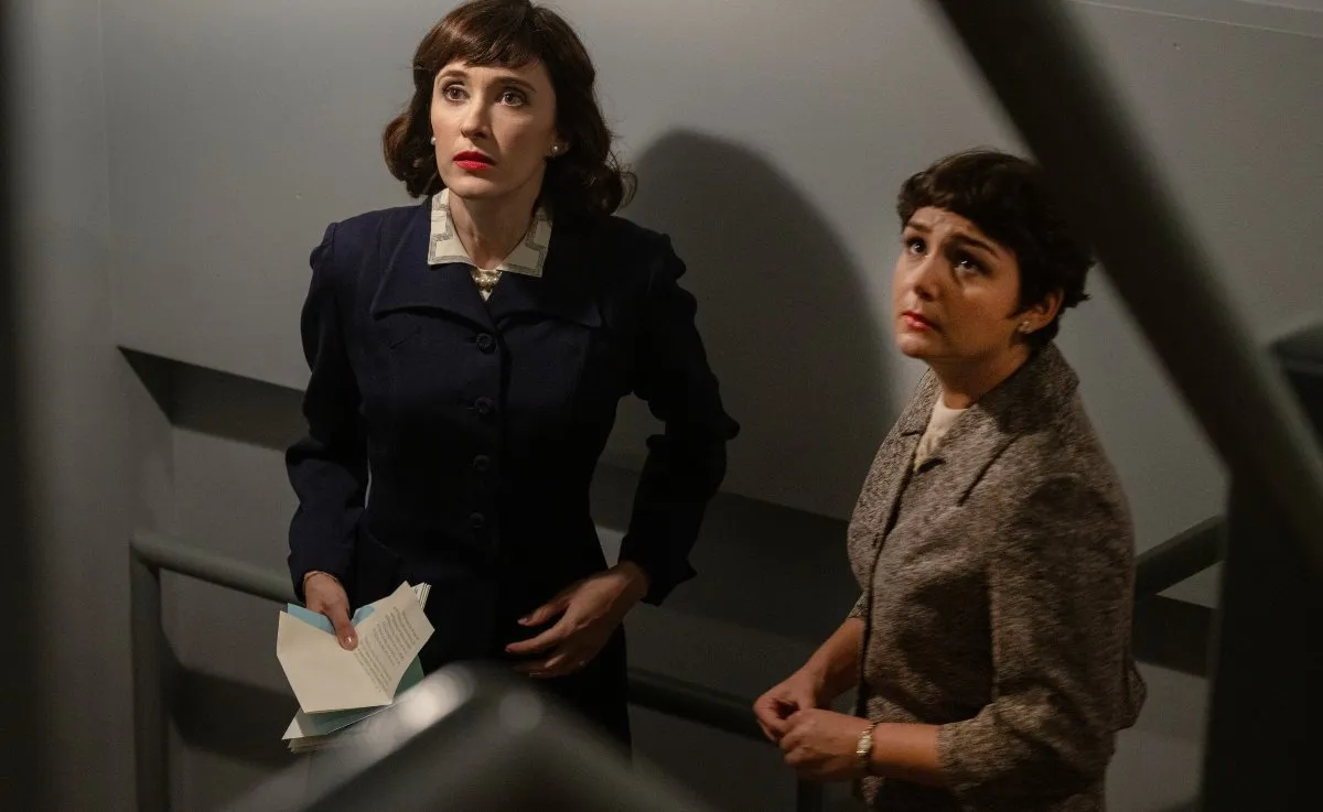 Two women stand in a stairwell looking upset in 'Fellow Travelers.'