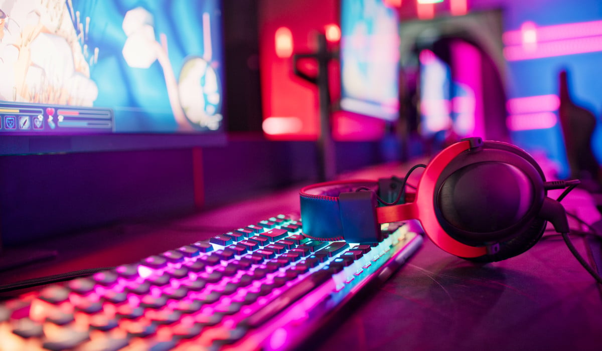 A colorful neon gaming setup with a monitor, keyboard, and headphones