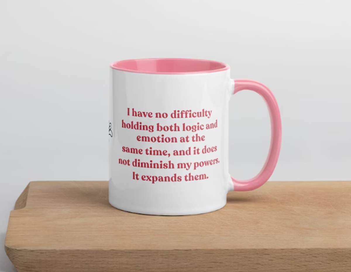 white mug with pink trim that says "I have no difficulty holding both logic and emotion at the same time, and it does not diminish my powers. It expands them"