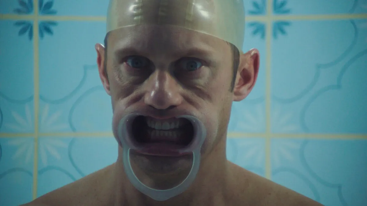 Alexander Skarsgård with plastic cap on and plastic device holding his mouth open in 'Infinity Pool" movie.