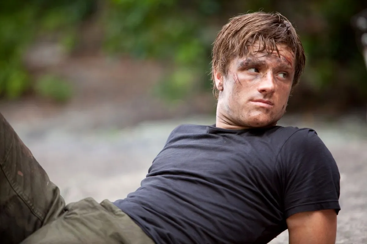 Josh Hutcherson as Peeta Mellark, a man leans back on the ground in 'The Hunger Games.'
