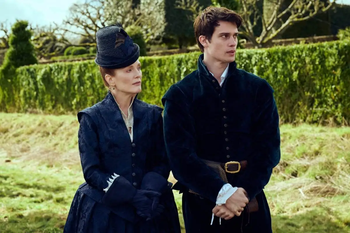 Julianne Moore and Nicholas Galitzine, an older white woman walks in a garden with a younger white man in period clothes in 'Mary and George.'