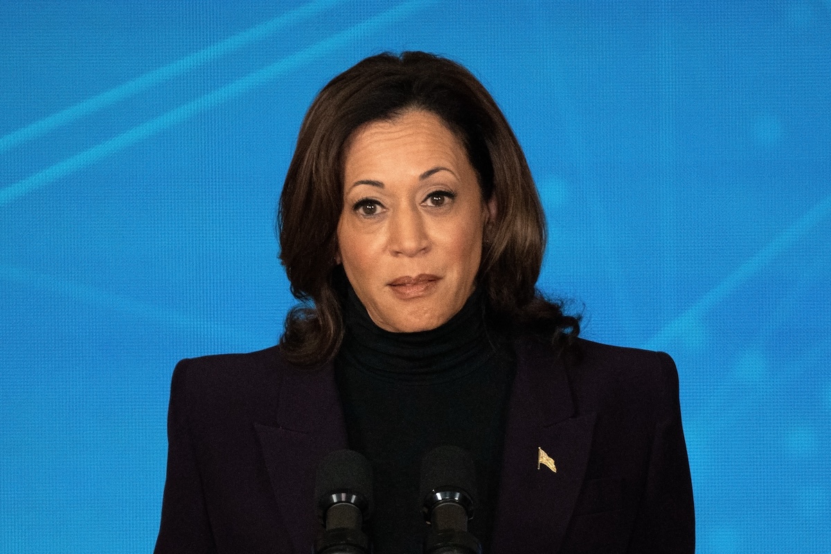 Kamala Harris stands in front of a blue background, with a slightly irritated expression.