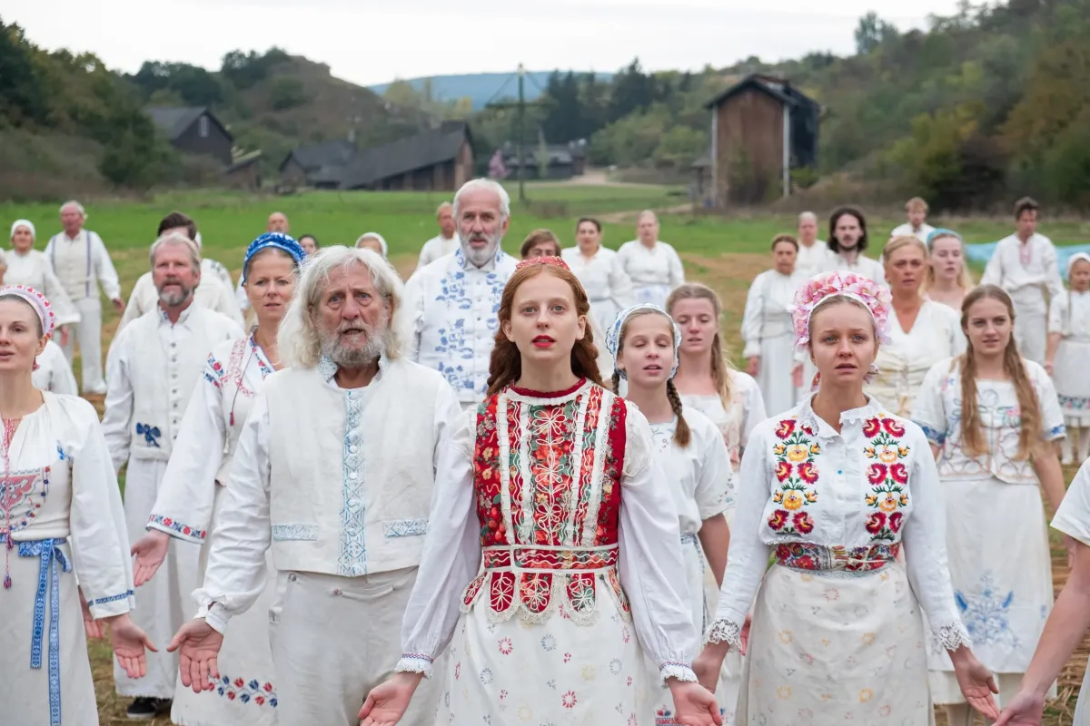 A group of Swedish people dressed in white traditional garments celebrate in 'Midsommar'