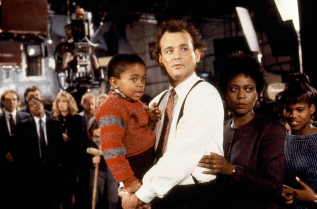 Bill Murray holds a child as the boy's mom looks on in Scrooged