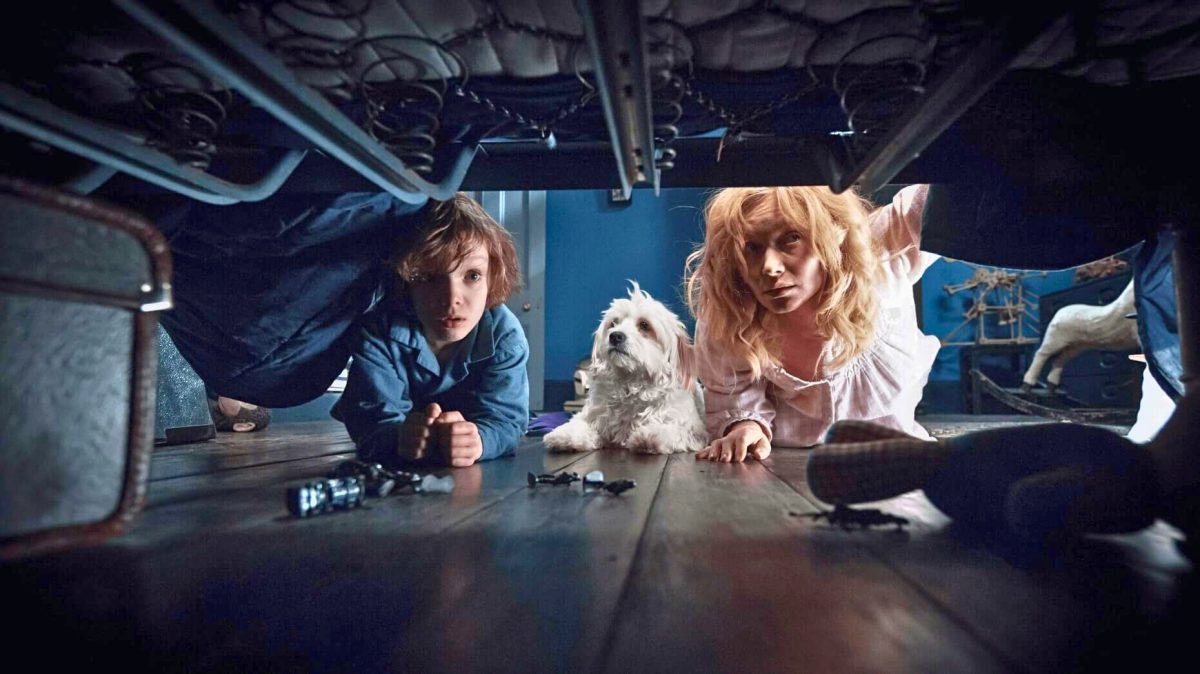 A mother, son, and dog peer underneath a bed in 'The Babadook'