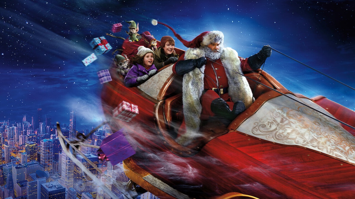 Santa flies his sleigh with two kids in the back and presents flying out 