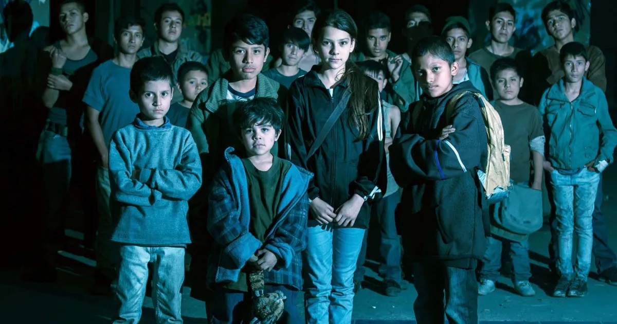 The five young protagonists of 'Tigers Are Not Afraid' (four boys, one girl in the center) stand together in front of a larger group of boys behind them. All of them are Mexican.