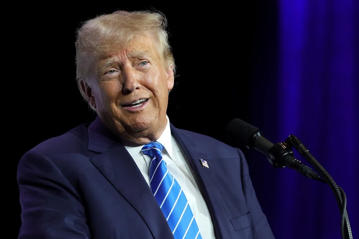 Trump on stage head and shoulders with blue background.