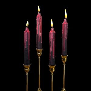 Black candles dripping red wax in brass candle sticks