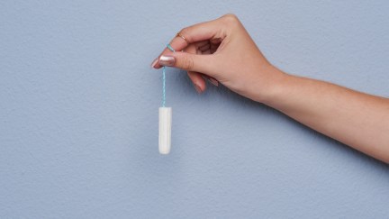 Cropped studio shot of a woman's hand holding a tampon against gray background
