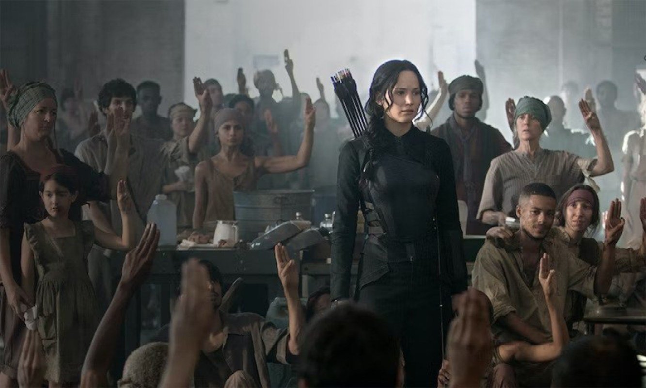 Image of District 8 from the Hunger Games Mockingjay; Jennifer Lawrence as Katniss stands in a room of poor garment workers.