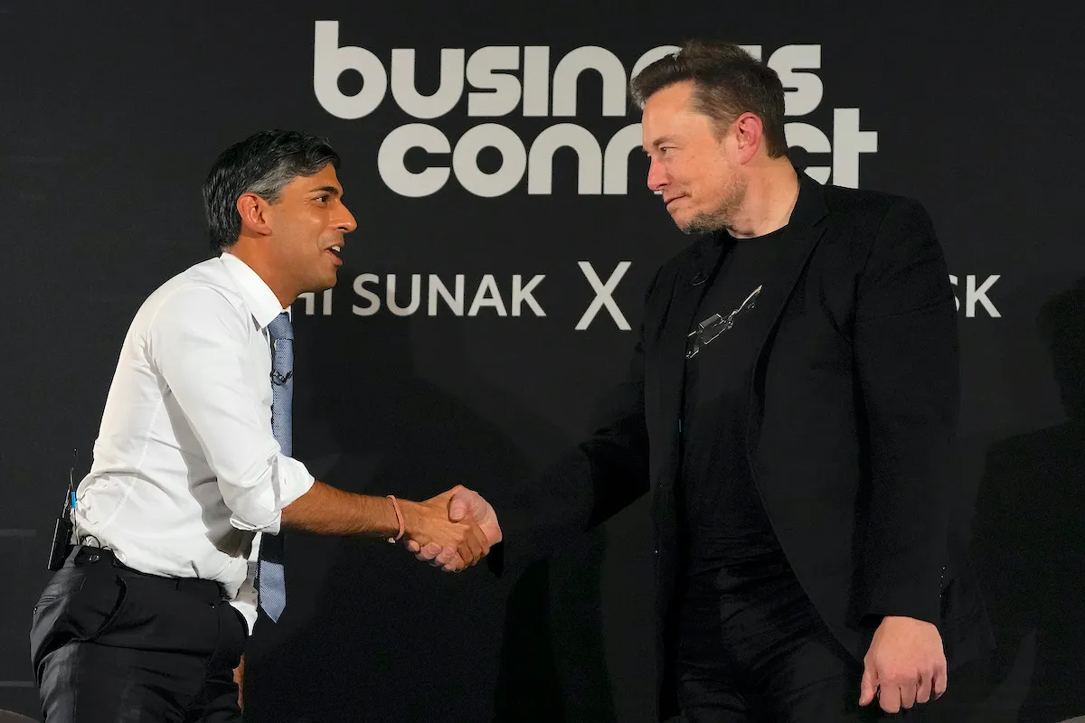 Rishi Sunak and Elon Musk shake hands in front of a backdrop reading "Business connect"