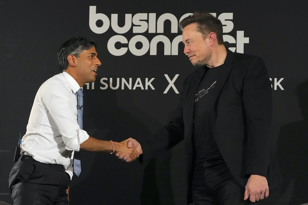 Rishi Sunak and Elon Musk shake hands in front of a backdrop reading "Business connect"
