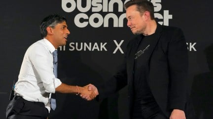 Rishi Sunak and Elon Musk shake hands in front of a backdrop reading 