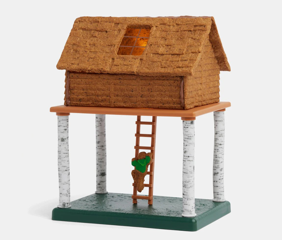 A gingerbread tree house complete with ladder and little figure.
