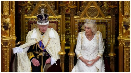 King Charles sits in a gold chair in fancy robes with a crown on his head next to queen consort Camilla who also sports a lavish gown and crown against a gold backdrop at the opening of British parliament.