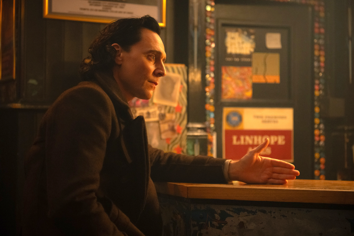 Loki sits at a bar, talking to Sylvie, who's off camera.