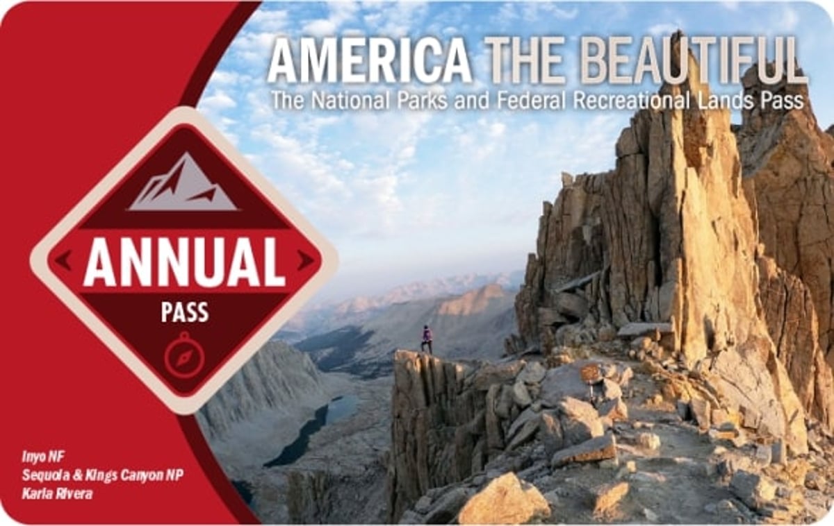 A credit card shaped image with a photograph of a mountain against the sky and a red border on one side. A diamond shaped logo that says annual pass is half in the red border and half in the picture.