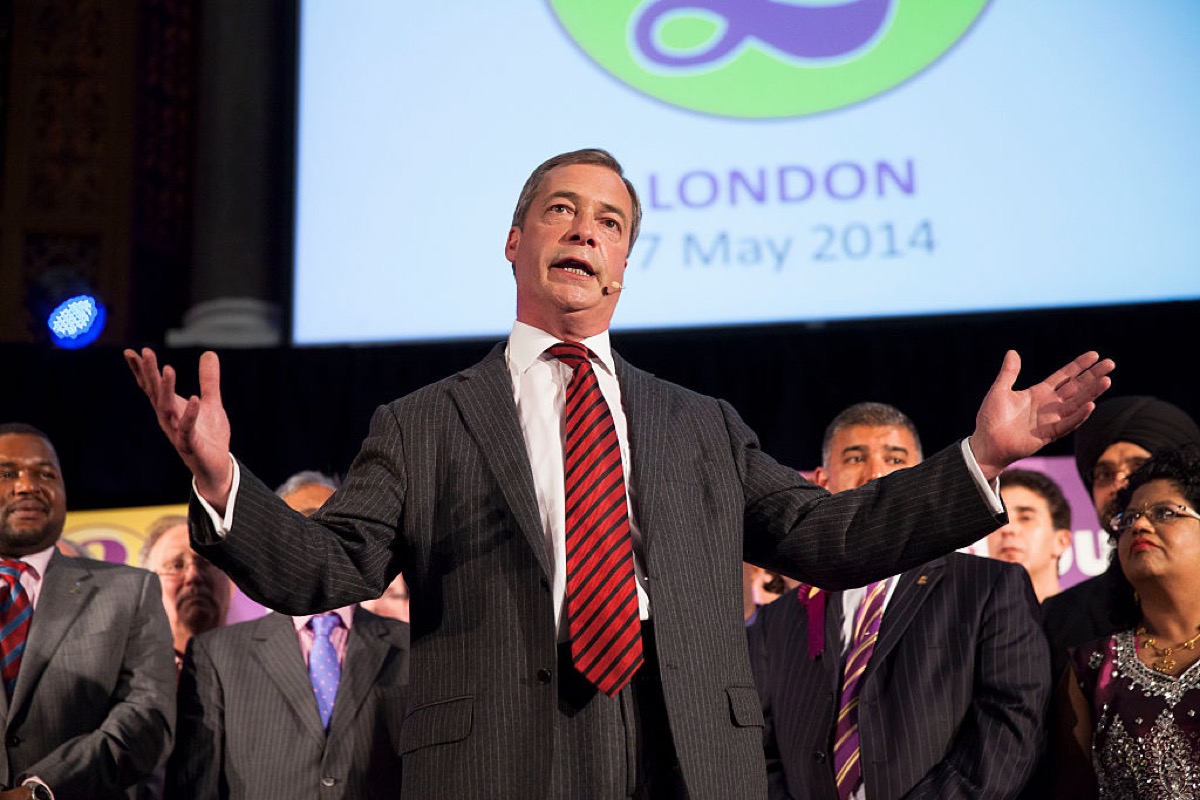 Nigel Farage making a doofusy gesture while speaking at an event.