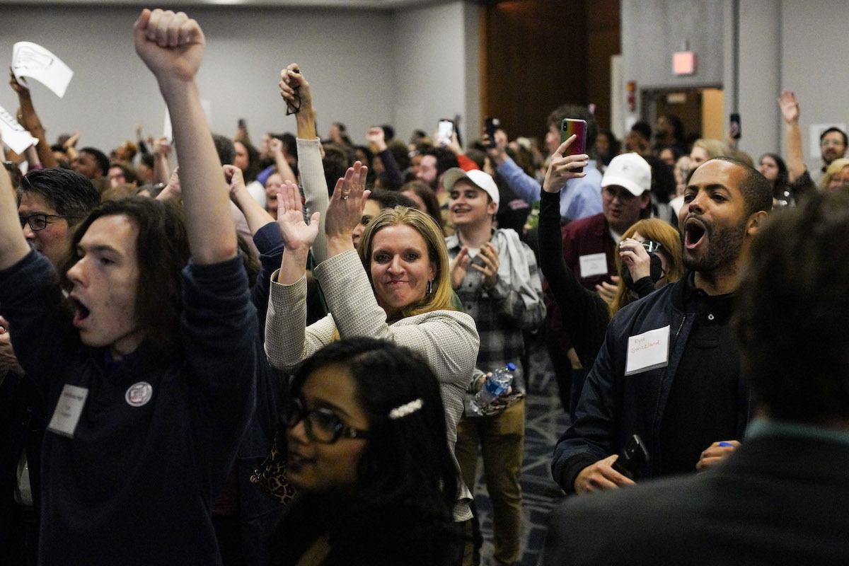 A group of people cheer and celebrate at an election watch event.